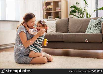 pregnancy, people and family concept - happy pregnant mother and little daughter with soap bubbles hugging at home. pregnant mother and daughter with soap bubbles