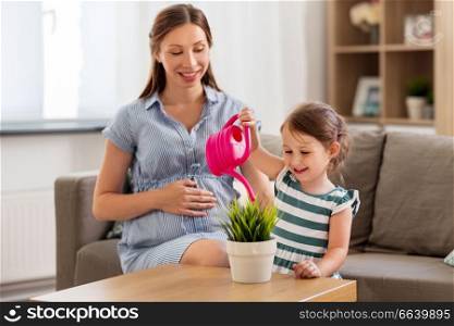 pregnancy, people and family concept - happy pregnant mother and little daughter with home plant and watering can. pregnant mother and daughter watering home plant