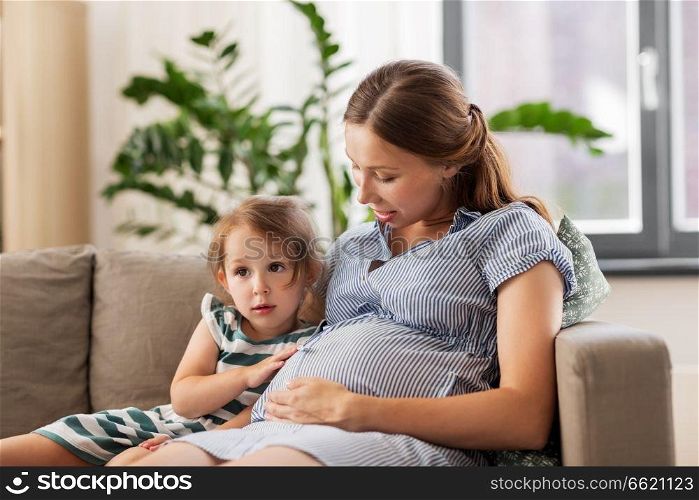 pregnancy, people and family concept - happy pregnant mother and little daughter at home. pregnant mother and daughter at home