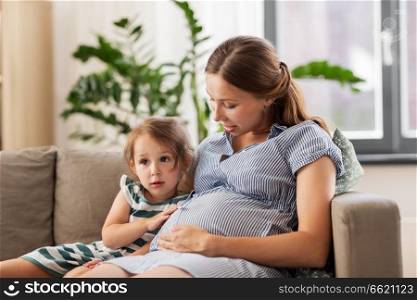 pregnancy, people and family concept - happy pregnant mother and little daughter at home. pregnant mother and daughter at home