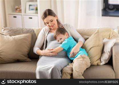 pregnancy, people and family concept - happy pregnant mother and little son hugging at home. happy pregnant mother and son hugging at home