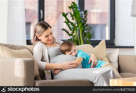 pregnancy, people and family concept - happy pregnant mother and little son hugging at home. happy pregnant mother and son hugging at home. happy pregnant mother and son hugging at home