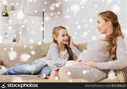 pregnancy, people and family concept - happy pregnant woman with girl sitting on sofa and talking at home over snow. happy pregnant woman and girl on sofa at home