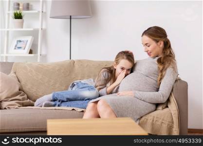 pregnancy, people and family concept - happy pregnant woman with girl talking to baby in belly at home. pregnant woman and girl talking to baby in belly