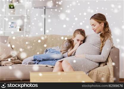 pregnancy, people and family concept - happy pregnant woman with girl talking to baby in belly at home over snow. pregnant woman and girl talking to baby in belly