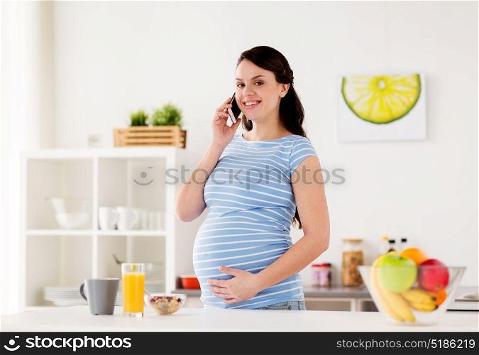 pregnancy, people and healthy eating concept - happy pregnant woman calling on smartphone and having breakfast at home kitchen. happy pregnant woman calling on smartphone at home
