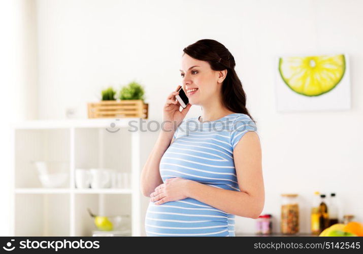 pregnancy, people and healthy eating concept - happy pregnant woman calling on smartphone at home kitchen. happy pregnant woman calling on smartphone at home