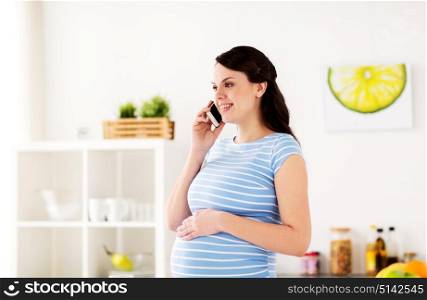 pregnancy, people and healthy eating concept - happy pregnant woman calling on smartphone at home kitchen. happy pregnant woman calling on smartphone at home