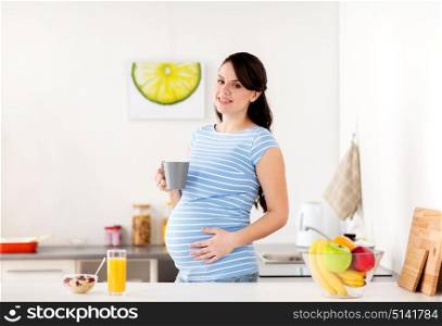 pregnancy, people and healthy eating concept - happy pregnant woman with cup of tea and food having breakfast at home kitchen. happy pregnant woman with cup at home kitchen