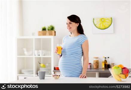 pregnancy, people and healthy eating concept - happy pregnant woman with glass of orange juice and muesli having breakfast at home kitchen. happy pregnant woman having breakfast at home
