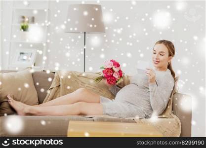 pregnancy, people and holidays concept - happy pregnant woman with flowers and greeting card at home over snow. happy pregnant woman with flowers and card at home