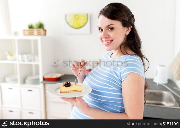 pregnancy, people and junk food concept - happy pregnant woman eating cake at home kitchen. happy pregnant woman eating cake at home kitchen