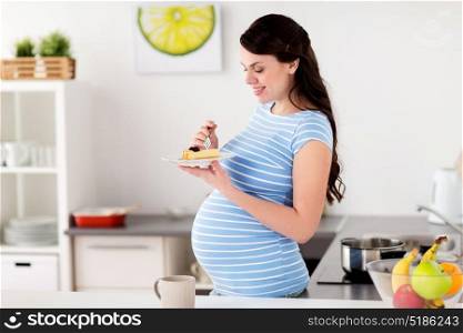 pregnancy, people and junk food concept - happy pregnant woman eating cake at home kitchen. happy pregnant woman eating cake at home kitchen
