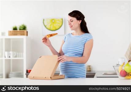 pregnancy, people and junk food concept - happy pregnant woman eating pizza at home kitchen. happy pregnant woman eating pizza at home kitchen