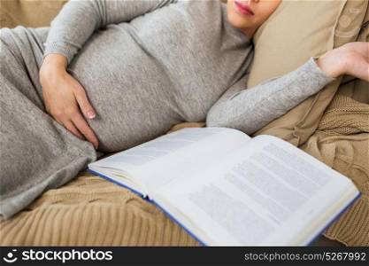 pregnancy, people and motherhood concept - close up of pregnant woman with book sleeping at home. close up of pregnant woman with book sleeping