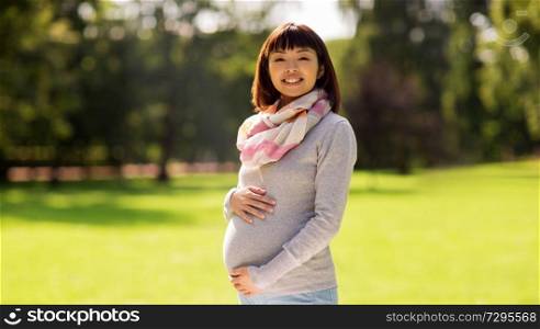 pregnancy, people and motherhood concept - happy pregnant asian woman at park. happy pregnant asian woman at park