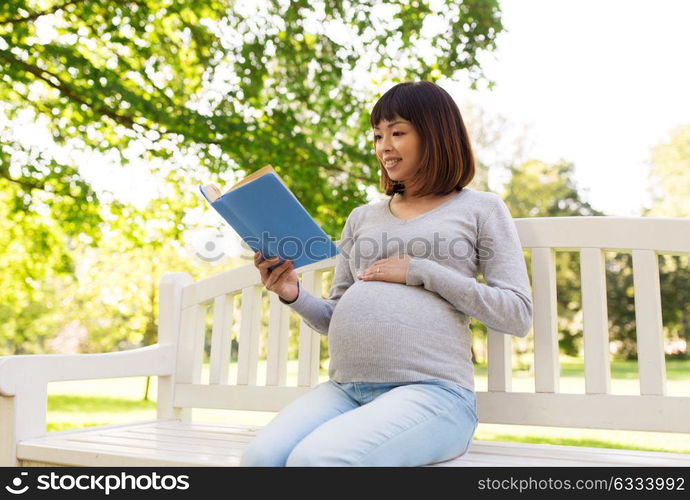 pregnancy, people and motherhood concept - happy pregnant asian woman sitting on park bench and reading book. happy pregnant asian woman reading book at park