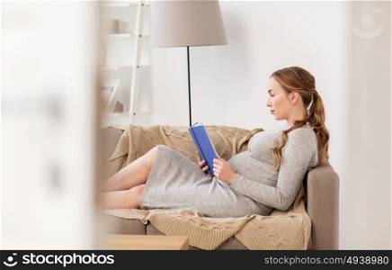 pregnancy, people and motherhood concept - pregnant woman lying on sofa and reading book. pregnant woman reading book at home