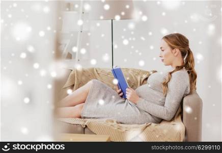 pregnancy, people and motherhood concept - pregnant woman lying on sofa and reading book over snow. pregnant woman reading book at home