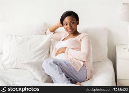pregnancy, people and rest concept - happy pregnant african american woman lying in bed at home bedroom. happy pregnant african woman lying in bed at home