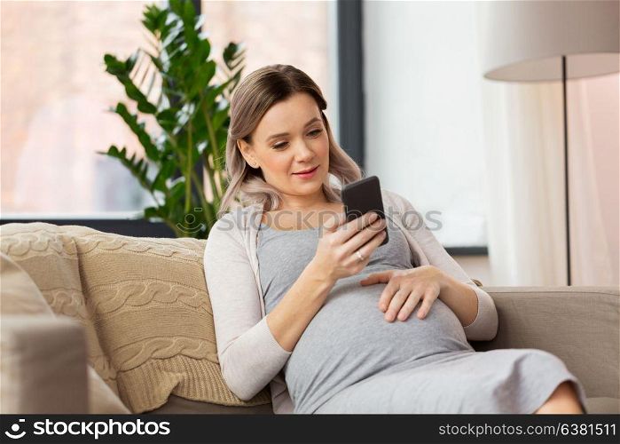 pregnancy, people and technology concept - happy pregnant woman with smartphone at home. happy pregnant woman with smartphone at home