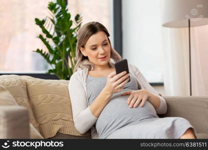 pregnancy, people and technology concept - happy pregnant woman with smartphone at home. happy pregnant woman with smartphone at home