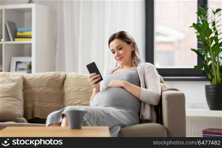 pregnancy, people and technology concept - happy pregnant woman with smartphone at home. happy pregnant woman with smartphone at home. happy pregnant woman with smartphone at home