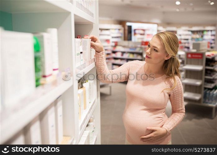 pregnancy, people, healthcare, beauty and bodycare concept - pregnant woman choosing medicine at pharmacy or cosmetics store. pregnant woman at pharmacy or cosmetics store