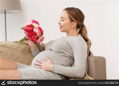 pregnancy, people, holidays and expectation concept - happy pregnant woman with flowers at home. happy pregnant woman with flowers at home