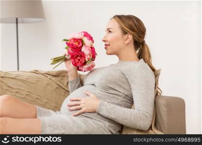 pregnancy, people, holidays and expectation concept - happy pregnant woman with flowers at home. happy pregnant woman with flowers at home