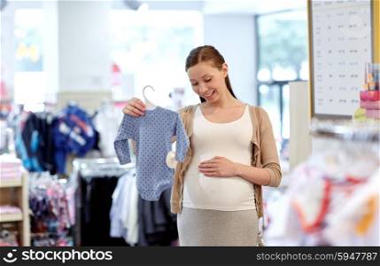 pregnancy, people, sale and expectation concept - happy pregnant woman shopping and buying baby bodysuit at children clothing store