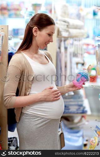 pregnancy, people, shopping, sale and expectation concept - happy pregnant woman choosing baby bottle at childrens store