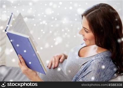 pregnancy, people, winter and motherhood concept - smiling pregnant woman lying on sofa and reading book over snow
