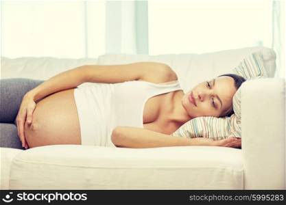 pregnancy, rest, people and expectation concept - happy pregnant woman lying on sofa at home