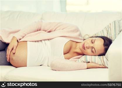 pregnancy, rest, people and expectation concept - happy pregnant woman sleeping on sofa at home