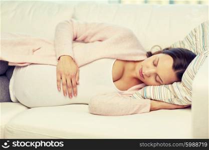 pregnancy, rest, people and expectation concept - happy pregnant woman sleeping on sofa at home