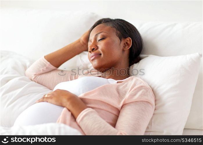 pregnancy, rest, people and expectation concept - pregnant african american woman sleeping in bed at home. pregnant african american woman sleeping at home