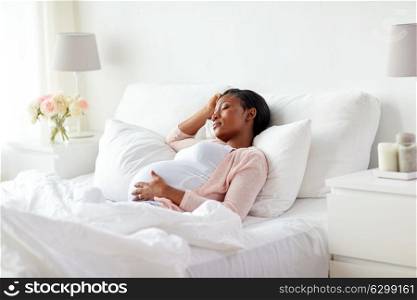 pregnancy, rest, people and expectation concept - pregnant african american woman sleeping in bed at home. pregnant african american woman sleeping at home