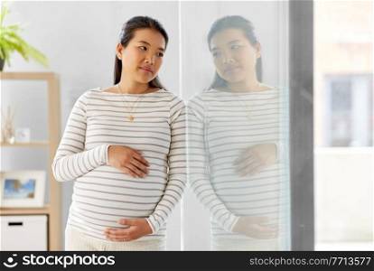 pregnancy, rest, people and expectation concept - pregnant asian woman touching her belly at home. pregnant asian woman at home