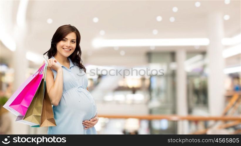 pregnancy, sale, motherhood, people and expectation concept - happy pregnant woman with shopping bags touching her big belly over mall background