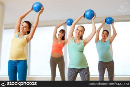 pregnancy, sport, fitness and healthy lifestyle concept - group of happy pregnant women training with small exercise balls in gym. pregnant women training with exercise balls in gym