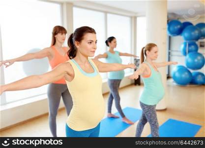 pregnancy, sport, fitness and healthy lifestyle concept - group of happy pregnant women exercising in gym. happy pregnant women exercising in gym
