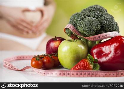 Pregnancy, sport, fitness, healthy lifestyle concept . Pregnant woman with fruit and vegetables