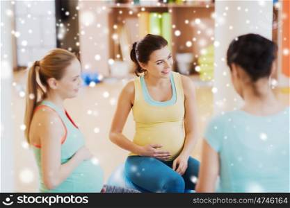 pregnancy, sport, fitness, people and healthy lifestyle concept - group of happy pregnant women sitting and talking on balls in gym over snow