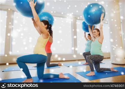 pregnancy, sport, fitness, people and healthy lifestyle concept - group of happy pregnant women exercising with stability ball in gym over snow
