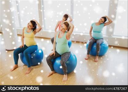 pregnancy, sport, fitness, people and healthy lifestyle concept - group of happy pregnant women exercising on stability balls in gym over snow
