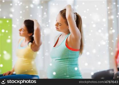 pregnancy, sport, fitness, people and healthy lifestyle concept - group of happy pregnant women exercising in gym over snow