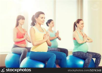 pregnancy, sport, fitness, people and healthy lifestyle concept - group of happy pregnant women exercising on ball in gym. happy pregnant women exercising on fitball in gym