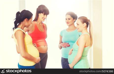 pregnancy, sport, fitness, people and healthy lifestyle concept - group of happy pregnant women talking in gym. group of happy pregnant women talking in gym