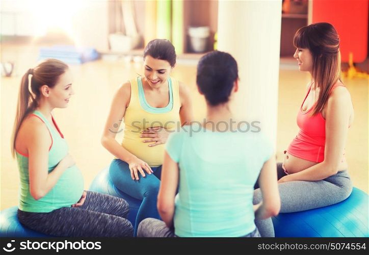 pregnancy, sport, fitness, people and healthy lifestyle concept - group of happy pregnant women sitting and talking on balls in gym. happy pregnant women sitting on balls in gym